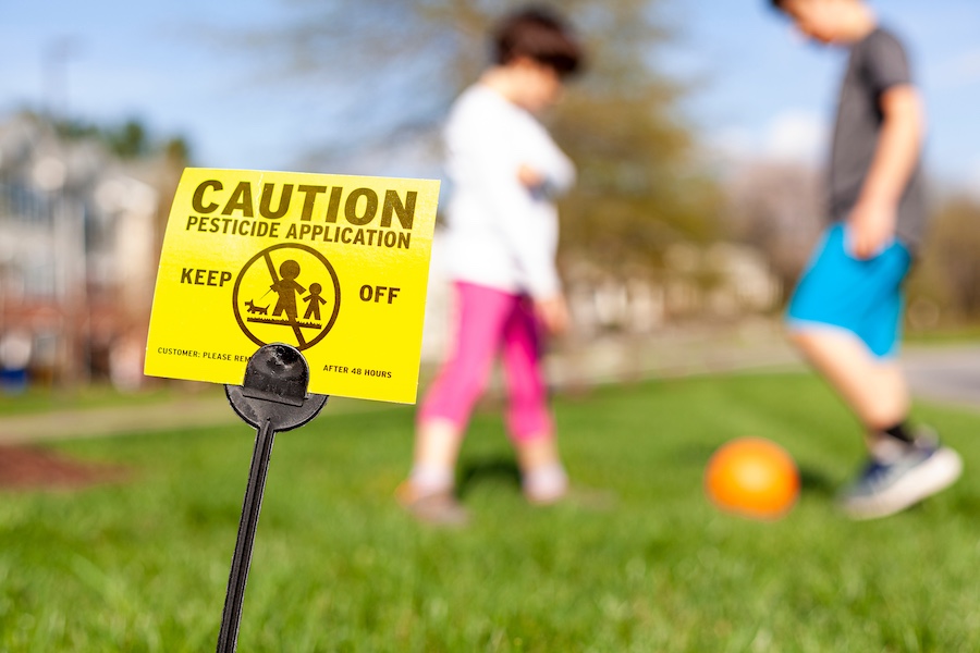 A yellow yard sign warning kids and pets of recent pesticide spraying
