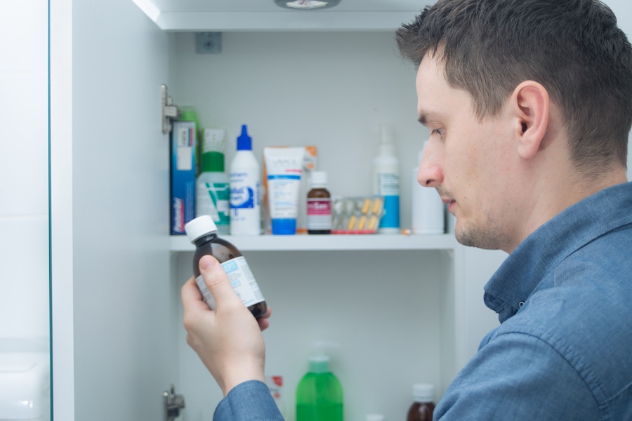 Man hold medication bottle reading instruction or prescription on packaging