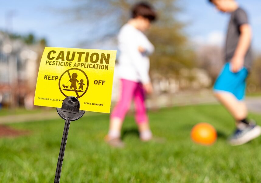 A yellow yard sign warning kids and pets of recent pesticide spraying
