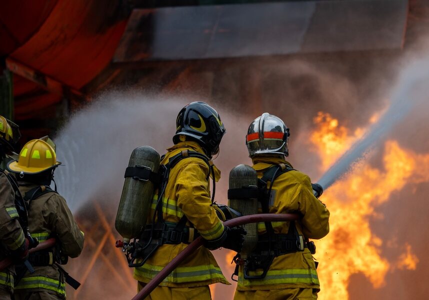 Team of firefighter in fireproof clothes using fog watering hose to put out the burning crashing plane with high flame for fire extinguish risk rescue mission and accident
