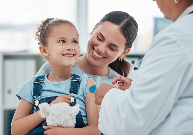 child with mother receiving a flu shot.