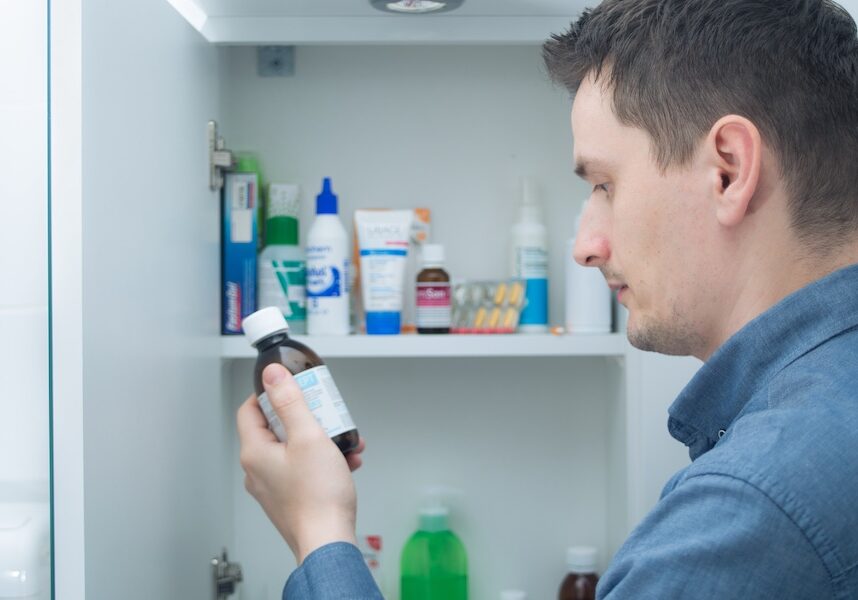 Man hold medication bottle reading instruction or prescription on packaging