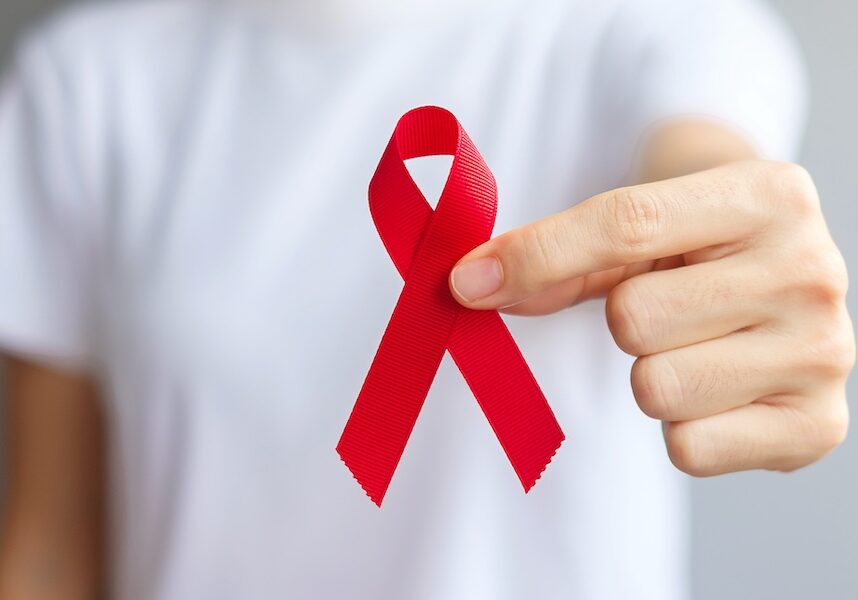 Hand holding Red Ribbon for HIV Testing