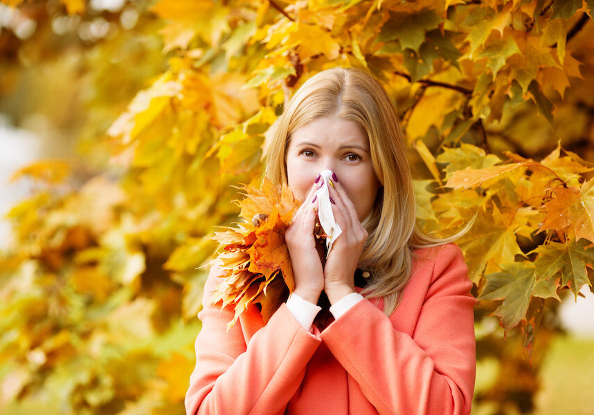 Woman with a cold on autumn background