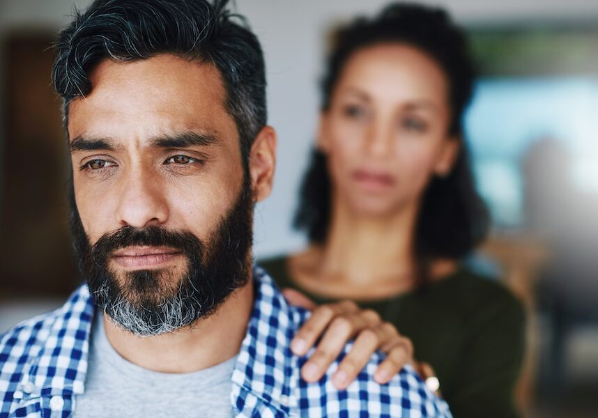 Support, sad and woman comforting a man with anxiety, depression or mental health problem. Thinking, love and a couple with care, comfort and touching shoulder for concern while depressed at home.