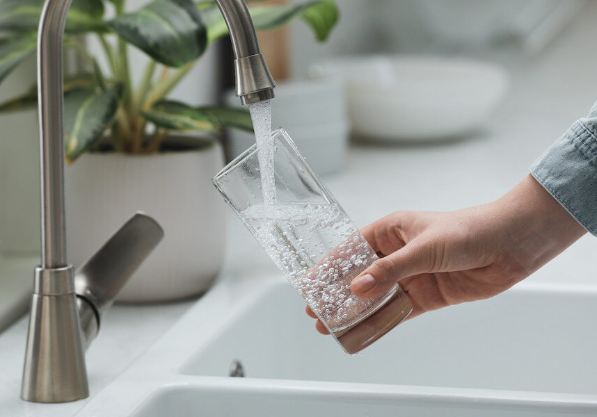 woman pouring glass of clean tap water